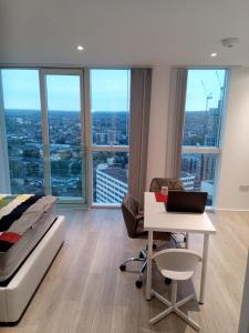 een slaapkamer met een bed en een bureau met een laptop bij 23 floor studio for work 1Gb WiFi in Croydon