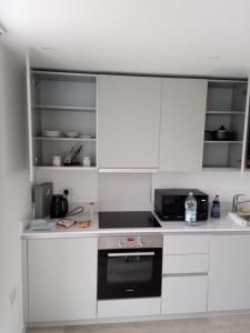 una cucina con armadi bianchi e piano cottura di 23 floor studio for work 1Gb WiFi a Croydon