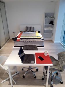 23 floor studio for work 1Gb WiFi في كرويدون: وجود سرير على طاولة بيضاء مع جهاز كمبيوتر محمول