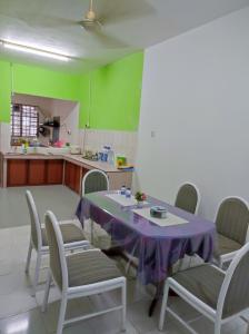 uma cozinha com uma mesa e cadeiras com uma toalha de mesa roxa em D'Hiquapis Homestay em Seri Manjung