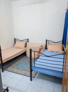 a room with two beds and a rug at D'Hiquapis Homestay in Seri Manjung
