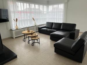 sala de estar con sofá negro y mesa en villa dunepanne en Adinkerke