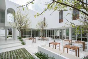 a courtyard with tables and benches in a building at Casa 33 Hatyai in Hat Yai