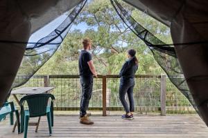 a man and a woman standing on a wooden deck at Lorne Bush House Cottages & Eco Retreats in Lorne