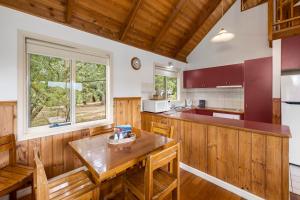 a kitchen with a wooden table and wooden chairs at Lorne Bush House Cottages & Eco Retreats in Lorne
