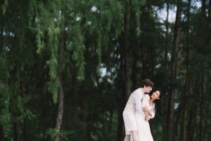 a bride and groom standing in front of a forest at Adang Island Resort in Ko Lipe