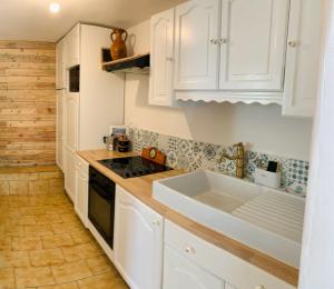 a kitchen with white cabinets and a sink at Cocoon’Ain*** Maison Chaleureuse Montagne/ViaRhona in Virignin