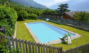 a swimming pool in a yard next to a fence at Mareinhof Vetzan-Apples,apartments&more in Silandro