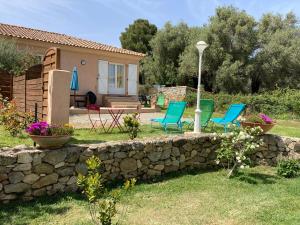 une cour avec des chaises et un mur en pierre dans l'établissement Appartement PALAZZI 2, à LʼÎle-Rousse