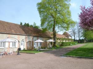 a building with tables and umbrellas in front of it at B&B Château De La Houssoye in La Houssoye