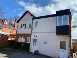 a white house with a black roof on a street at Spacious first floor apartment in the centre of Church Stretton with free parking in Church Stretton
