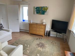 a living room with a television and a white couch at Spacious first floor apartment in the centre of Church Stretton with free parking in Church Stretton