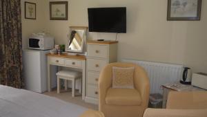 1 dormitorio con tocador, TV y silla en The Little Annexe, en Stamford