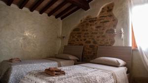a bedroom with two beds and a stone wall at Il Casale di Fiore in Cannara