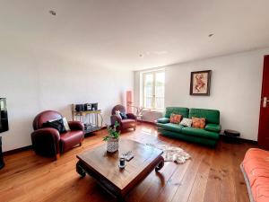 a living room with a green couch and chairs at Ferme de Mouline in Sainte-Foy-la-Longue