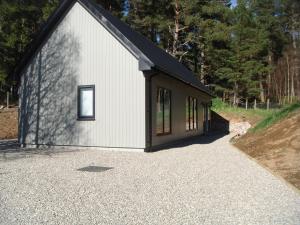 a small white building with a black roof at Sawmill Cottage in Grantown on Spey