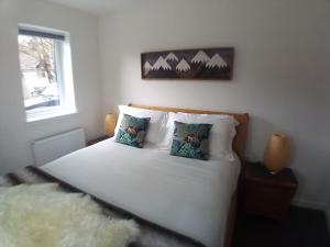 una camera da letto con un letto bianco con cuscini e una finestra di Sawmill Cottage a Grantown on Spey