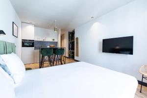 a bedroom with a white bed and a kitchen at Florella Croisette Apartment in Cannes