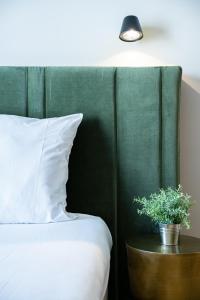 a bed with a green headboard and a potted plant at Florella Croisette Apartment in Cannes