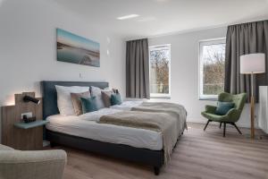 a bedroom with a large bed and a chair at Westside Arthotel in Kühlungsborn