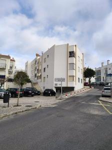 a white building with cars parked in a parking lot at The Light House II, with rooftop and parking in Nazaré
