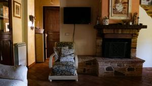 a living room with a fireplace and a chair and a television at Il Casale di Fiore in Cannara