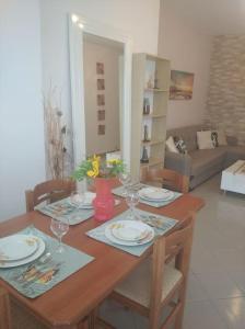 a dining room table with plates and wine glasses at Igli apartments in Arkasa