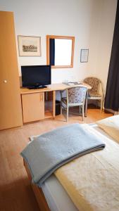 um quarto com uma secretária e uma mesa com uma televisão em Hotel Garni Zur Traube em Höhr-Grenzhausen
