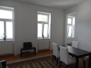 a dining room with a table and chairs and windows at Jugendstil Garconniere in Vienna