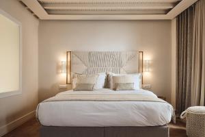 um quarto com uma cama grande com lençóis brancos e almofadas em AK Mykonos em Míconos