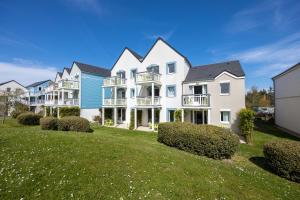 a large white house with balconies on a lawn at Les Ondines in Courseulles-sur-Mer