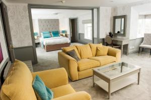 a living room with yellow furniture and a bedroom at Crown Hotel Wetheral in Carlisle