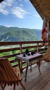 a table and chairs on a wooden deck with a view at Chateau Dio in Ambrolauri