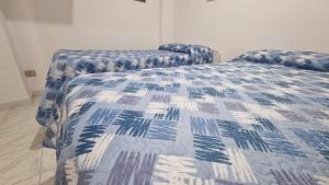 a bedroom with a bed with a blue and white comforter at Casa Marina Marzamemi in Marzamemi