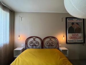 a bedroom with a yellow bed and a poster on the wall at La Casa all'ombra della Chiesa in Brescello