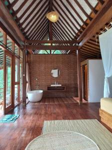 a bathroom with a tub in a room with wooden ceilings at Sang Tirta Resort in Penebel