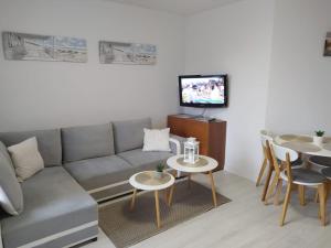 a living room with a couch and tables and a tv at Apartament przy plaży in Władysławowo