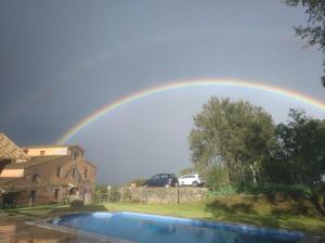 un arco iris en el cielo sobre una piscina en Can Pobric, en Maçanet de la Selva