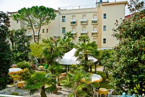 un edificio con mesas y sombrillas frente a un edificio en Hotel B&B Risorta en Abano Terme