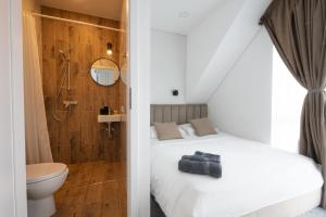 a bedroom with a white bed and a shower at Pajūrio Gintaro namai in Palanga