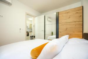 a bedroom with two white beds and a wooden headboard at Apartment Margarita in Zadar