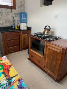 Una cocina con una estufa y una tetera sobre una encimera. en Casa aconchegante com piscina em Tiradentes, en Tiradentes