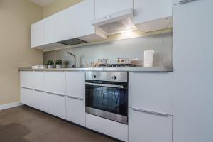 een keuken met witte kasten en een fornuis bij Holiday In Home Suite Archimede in Catania