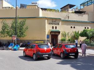 zwei rote Autos, die vor einem Gebäude geparkt sind in der Unterkunft Riad Andalib in Fès