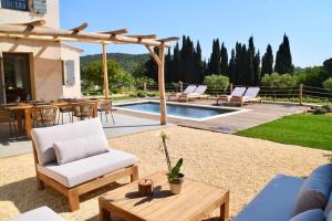 um pátio com uma mesa e cadeiras e uma piscina em Le Cabanon em Ramatuelle