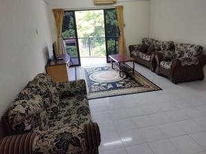 uma sala de estar com sofás e uma mesa num piso de azulejo em Lumut Valley em Lumut