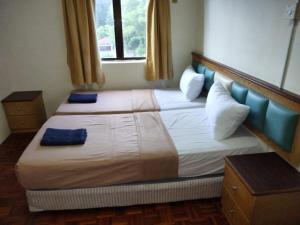 1 dormitorio con 2 camas con almohadas azules en Lumut Valley en Lumut