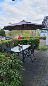 a table and chairs with an umbrella on a patio at Ferienwohnung im Sauerland - nähe Olpe (Biggesee) in Drolshagen