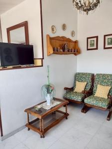 sala de estar con 2 sillas, mesa y TV en Precioso apartamento en San Vicente de O Grove, en San Vicente de O Grove
