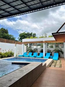 a pool with blue lounge chairs next to a house at Casa Cecilia Hotel in Bantay